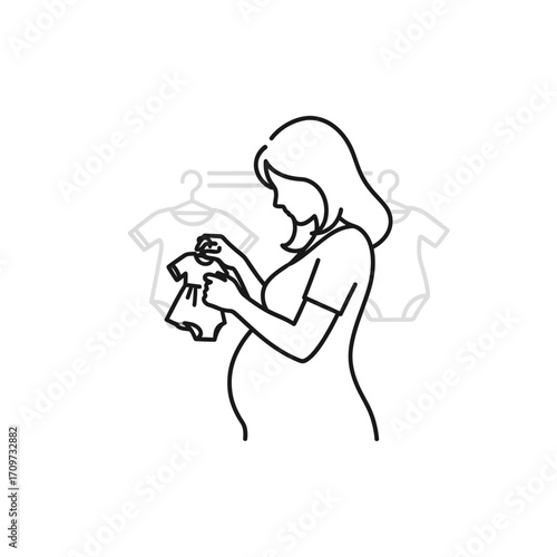 Pregnant woman gently examining tiny baby clothes, preparing for her newborn's arrival.