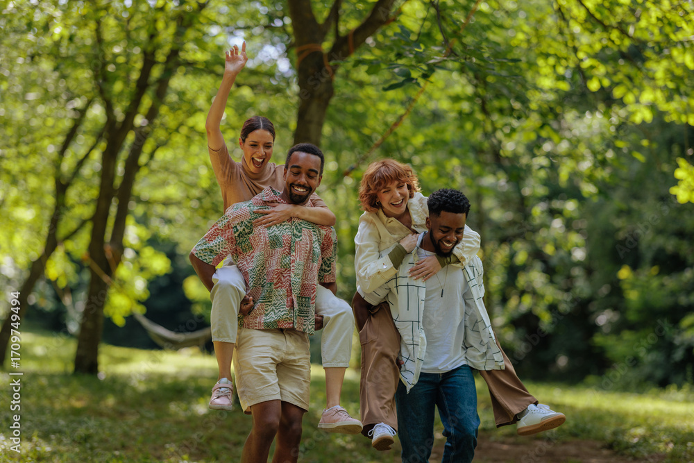 Obraz premium Two couples having a piggyback race in a park