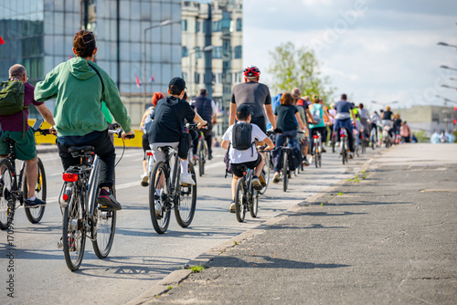 Children among group of cyclists on city road, street, asphalt