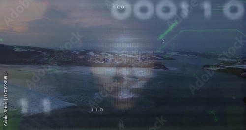 Floating projected male face hovering over arctic coast, with binary code and green HUD graphics