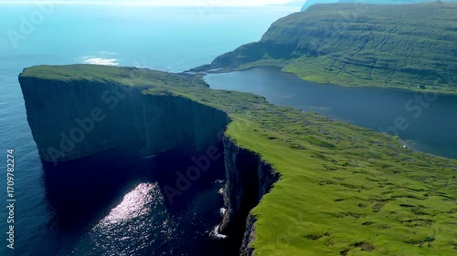 Stunning cliffs and lush greenery of the Faroe Islands in this aerial view. The serene waters reflect the vibrant landscape as the sun sets, creating a magical atmosphere. Sorvagsvatn lake, Vagar