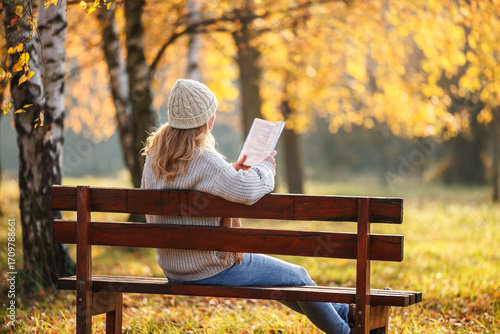 Photography Woman sitting on bench reading book in autumn park enjoying mindfulness and calm