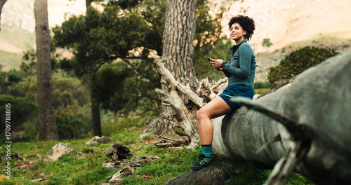 Tablou pe pânză Hiking, thinking and woman in forest, smartphone and relax with smile, social media and app for maps