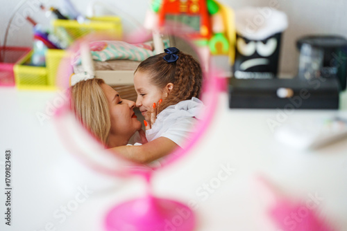 Mother and daughter share a joyful moment in a bright, colorful room