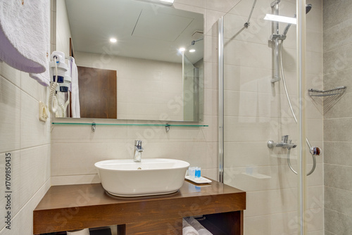 Wallpaper Mural A spacious modern bathroom with a clean design, featuring a glass shower, a wooden vanity unit, and tiled walls. The elegant fixture placement creates a comfortable and functional space. Torontodigital.ca