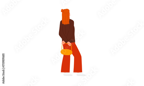 A woman with long red hair wearing a brown top and orange pants, holding a small yellow purse.