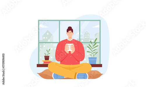 A calm person enjoys a warm beverage while sitting comfortably on a cushion by a window at home.