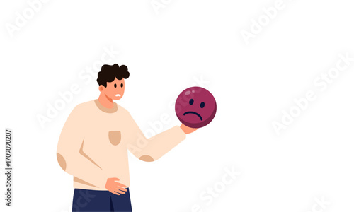 Man holding a sad face emoji, expressing negative emotion.