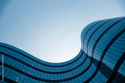 Curving blue building facade against a bright sky abstract architectural form