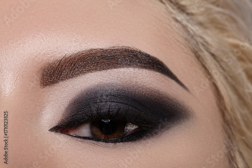 Closeup macro of female eye with bold dark smoky makeup and dramatic eyeliner. Editorial fashion look for runway, Halloween party, gothic style and mysterious vampire aesthetic