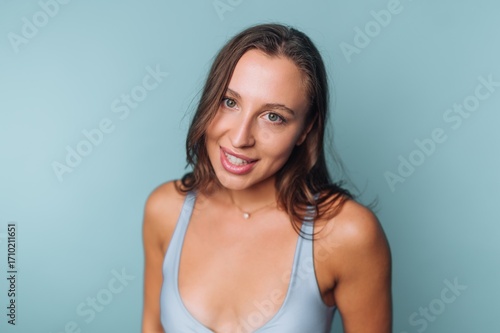 Woman smiling with a light blue background during a casual indoor portrait session in the afternoon light