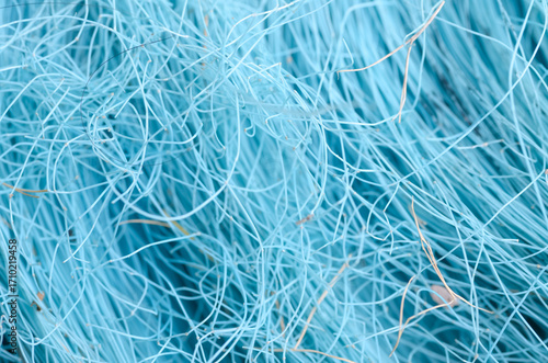 This abstract image showcases a dense, messy web of fine blue synthetic fibers, highlighting a vibrant and dynamic texture that fills the frame.