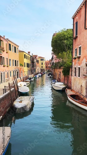 Old venetian architecture on the canal in Venice, Italy. Boats on the canal. Beautiful summer cityscape at sunny day. Famous travel destination. Vertical video
