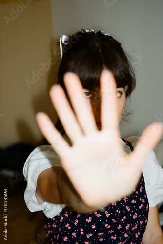 Young woman gestures with hand raised to express a boundary in an indoor setting