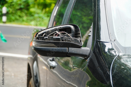 Fotografía A side mirror dangling loosely from a car, exposing wires and components