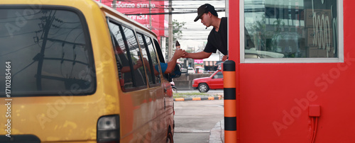 Hand Man in car receiving coffee in drive thru fast food restaurant. Staff serving takeaway order for driver in delivery window. Drive through and takeaway for buy fast food for protect covid19.