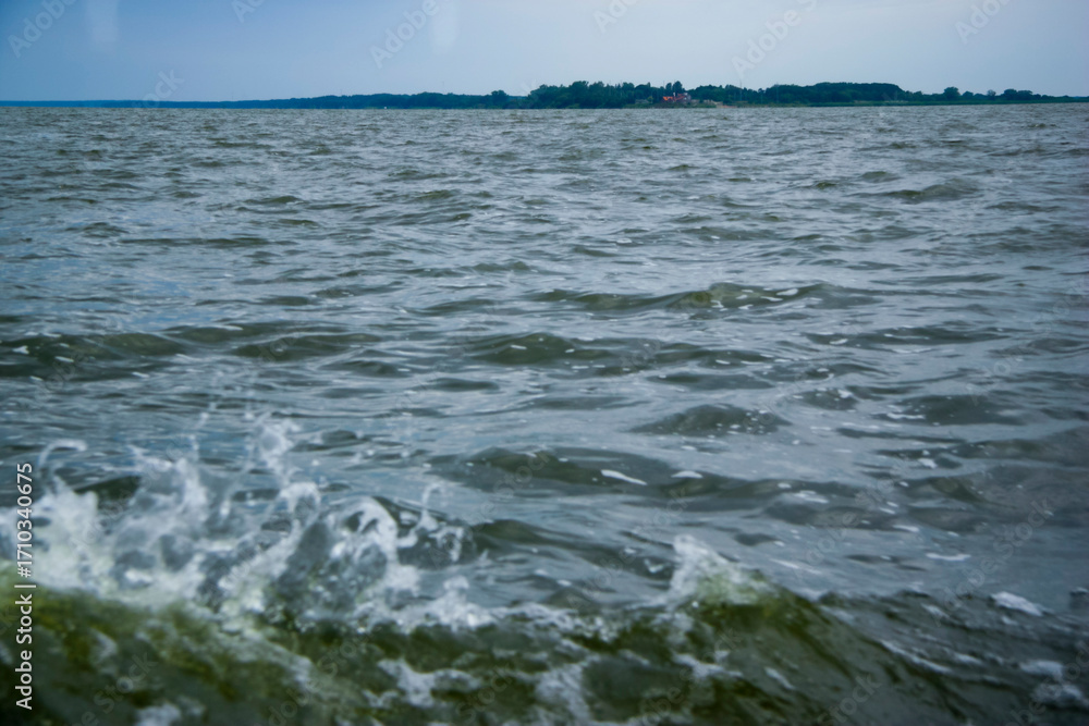 Fototapeta premium Vast expanse of open water with gentle waves and distant shoreline under a soft sky