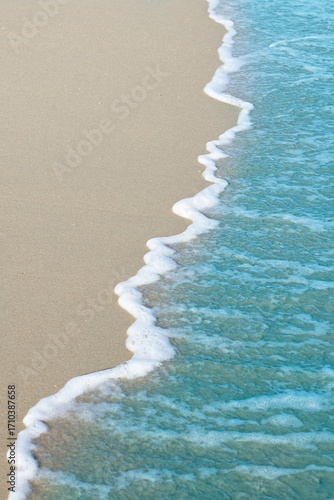 Gentle waves lapping on sandy beach create serene and calming scene
