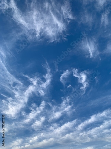 Blue sky with white cirrus clouds on a clear day. Natural background of soft cloudscape