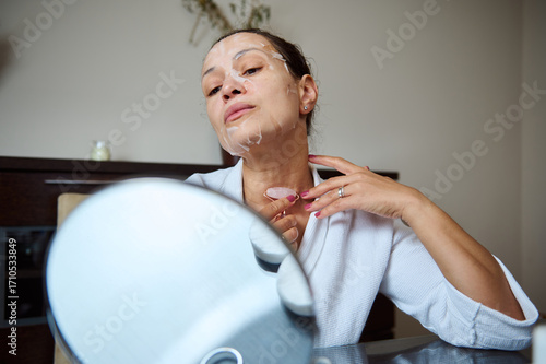 Woman Using Facial Roller and Mask in Her Skincare Routine at Home