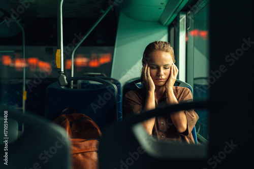 Tired woman commuting by bus at night, returning home from work in city public transport