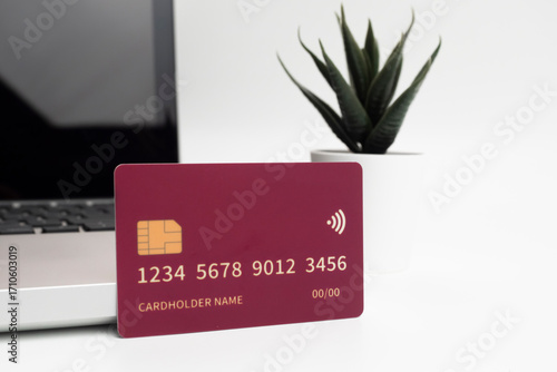 Debit and credit cards placed in front of a laptop. Online shopping and retail payment concepts. Mockups and fake credit cards. The credit cards are colored red.