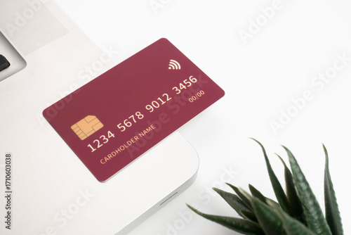 Debit and credit cards placed in front of a laptop. Online shopping and retail payment concepts. Mockups and fake credit cards. The credit cards are colored red.
