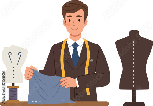 A smiling male tailor in a suit with a measuring tape, holding fabric, with dress forms and a mannequin in a workshop.