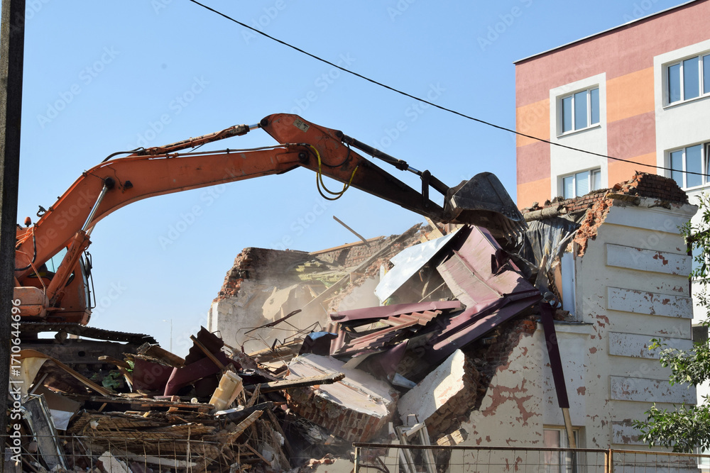 Fototapeta premium Residential construction. A modern excavator removes the remains of an old house.