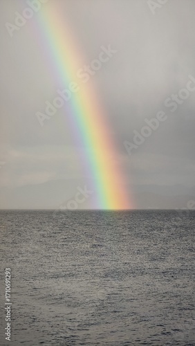 colorful rainbow arc above sea level ocean horizon dramatic sky weather
