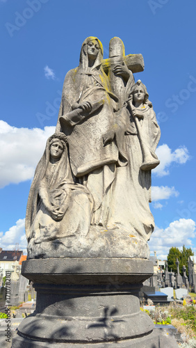 Billede på lærred Stone statue of allegorical religious figures with a cross in a historic cemeter