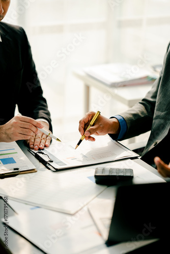 Young colleagues discuss business and analytical price charts using calculators and laptops to calculate financial, tax, accounting, statistics and analytical research ideas.