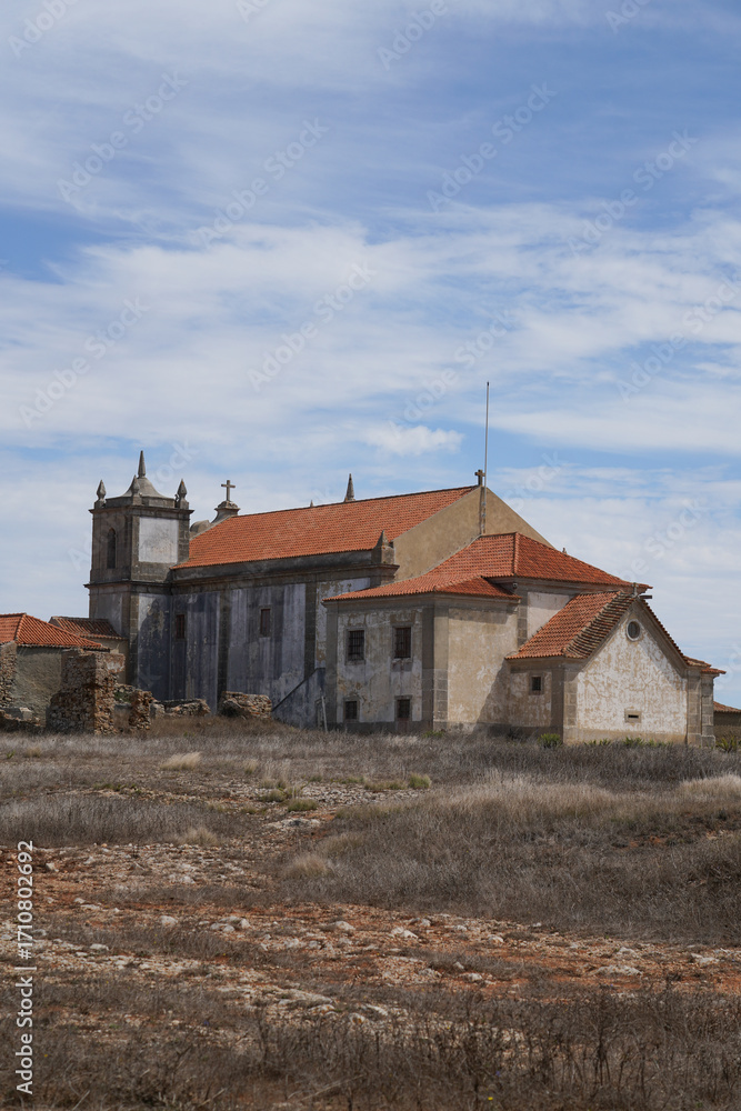 Fototapeta premium Old stone church with tiled roof at Cabo Espichel, Portugal. Historic architecture, dry landscape, religious symbolism, peaceful scene.