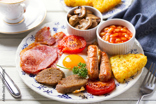 Classic traditional Irish or English breakfast with sausages, bacon rashers, white pudding, beans and grilled tomatoes