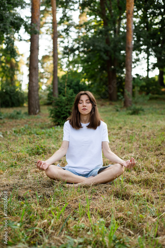 Young girl meditating with her eyes closed in the forest.