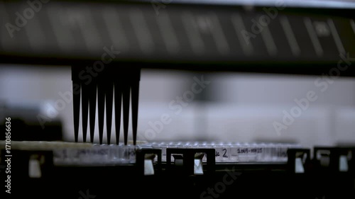 Close-up detailed view of a pipette extraction machine removing set volumes of liquid and dispensing them into other containers — perfect for themes of automation, precision, science, and chemistry.