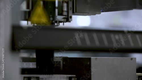 Close-up detailed view of a pipette extraction machine removing set volumes of liquid and dispensing them into other containers — perfect for themes of automation, precision, science, and chemistry.