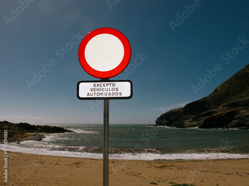 Señal de prohibido el paso en playa con fondo de mar y montañas