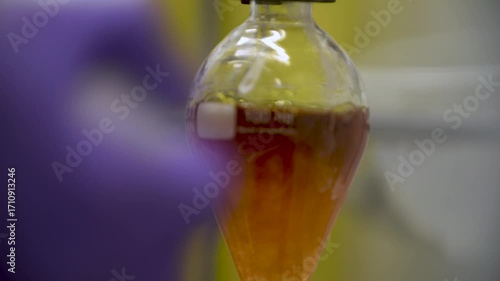 Close-up detailed view of a chemist pouring liquid into a pear-shaped flask, triggering a chemical reaction and color change — perfect for themes of chemistry, science, experimentation, and precision.
