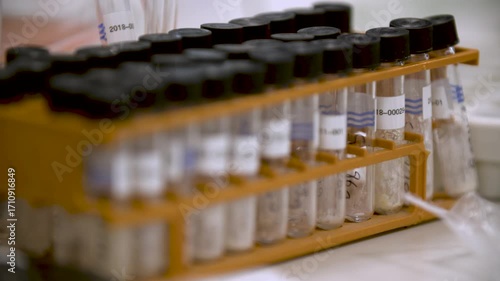 Close-up detailed view of multiple small labelled lidded flasks in a box in a laboratory, showing themes of scientific testing, organization, and precision.