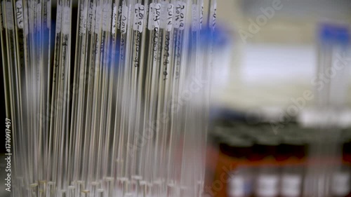Camera pans between close-up thin labeled science flasks and a wider view of many flasks stored in the background of the laboratory — themes of research, storage, chemistry, and laboratory order