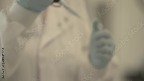 Close-up detailed view of a woman in disposable science gloves using an electronic pipette to measure liquid volume from a small flask in a laboratory — themes of science, chemistry, precision. 