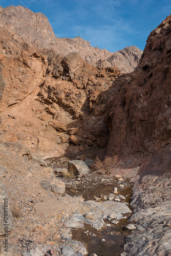 Rocky desert canyon with a small stream flowing through rugged mountains near Yazd, Iran, showcasing dramatic arid landscape and natural wilderness beauty.