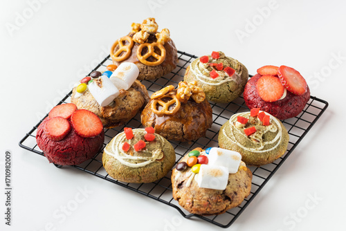Assortment of fresh chocolate American chip cookies with salted camel, caramel popcorn, matcha tea , marshmallow and colorful candies on white background. Different cookies on cooling rack