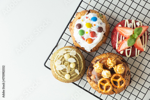 Assortment of fresh chocolate American chip cookies with salted camel, caramel popcorn, matcha tea , marshmallow and colorful candies on white background. Flat lay of different cookies on cooling rack