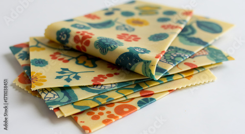 A stack of beautifully patterned, eco-friendly beeswax food wraps, showcasing various floral and botanical designs