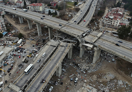Devastating earthquake damage to an elevated highway overpass with vehicles visible