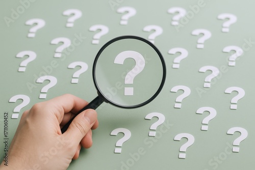 Magnifying Glass Over Question Marks Concept: Exploring Answers, Curiosity and Information Seeking on Green Background