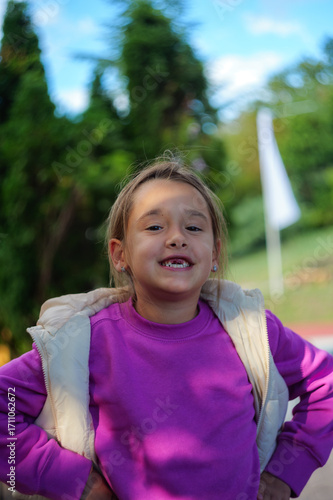 Young girl smiling with missing teeth in a park