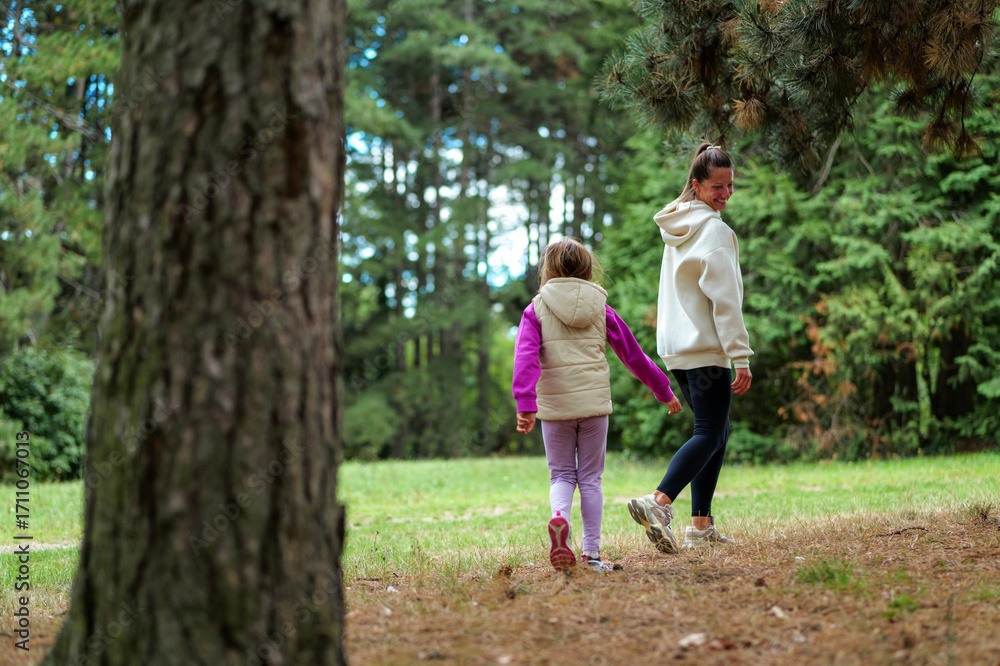 Fototapeta premium Mother and daughter walking in forest, enjoying nature together